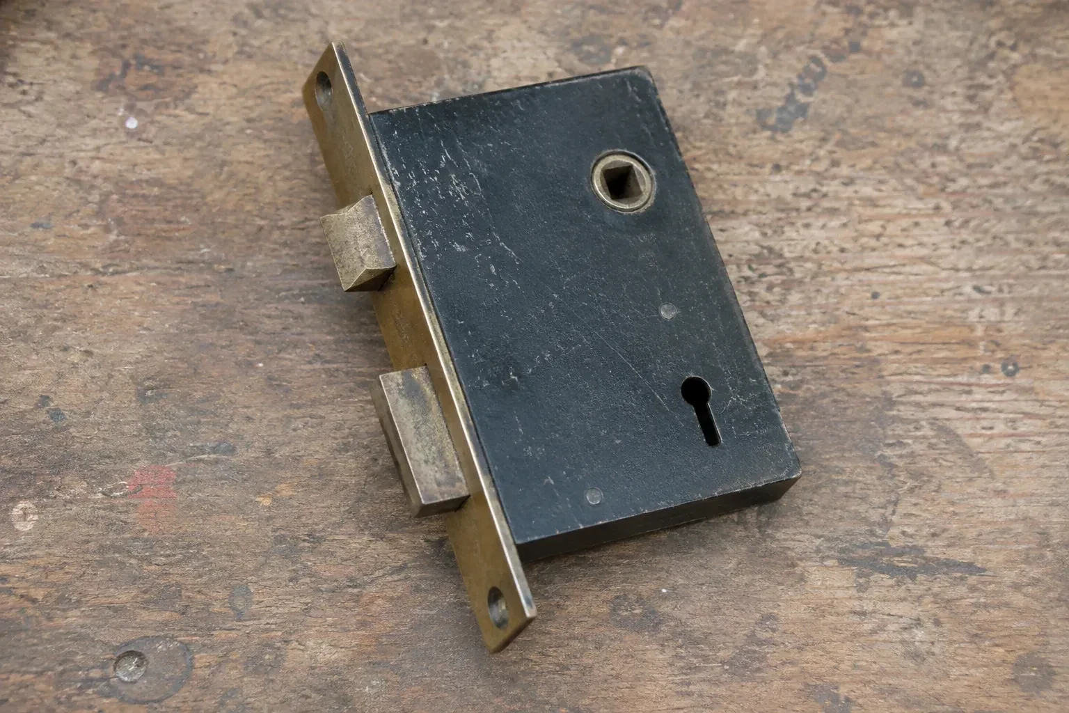 Closed mortise lock case with spindle opening, keyhole, latch and deadbolt on a wooden workbench. — Vintage Mortise Lock Service, Martin Grove Gardens